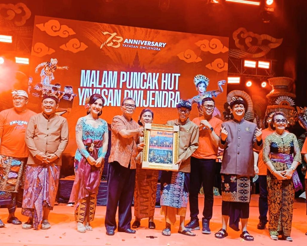 Ketua Yayasan THK, I Gusti Ngurah Wisnu Wardana saat menyerahkan mockup tabloid pariwisata Bali Travel Newspaper kepada Ketua Pengurus Yayasan Dwijendra, Dr. I Nyoman Satia Negara dalam Peringatan Hari Ulang Tahun (HUT) Ke-73 Yayasan Dwijendra Denpasar, Rabu (28/1/2026) malam. (Balihotnews/tim)