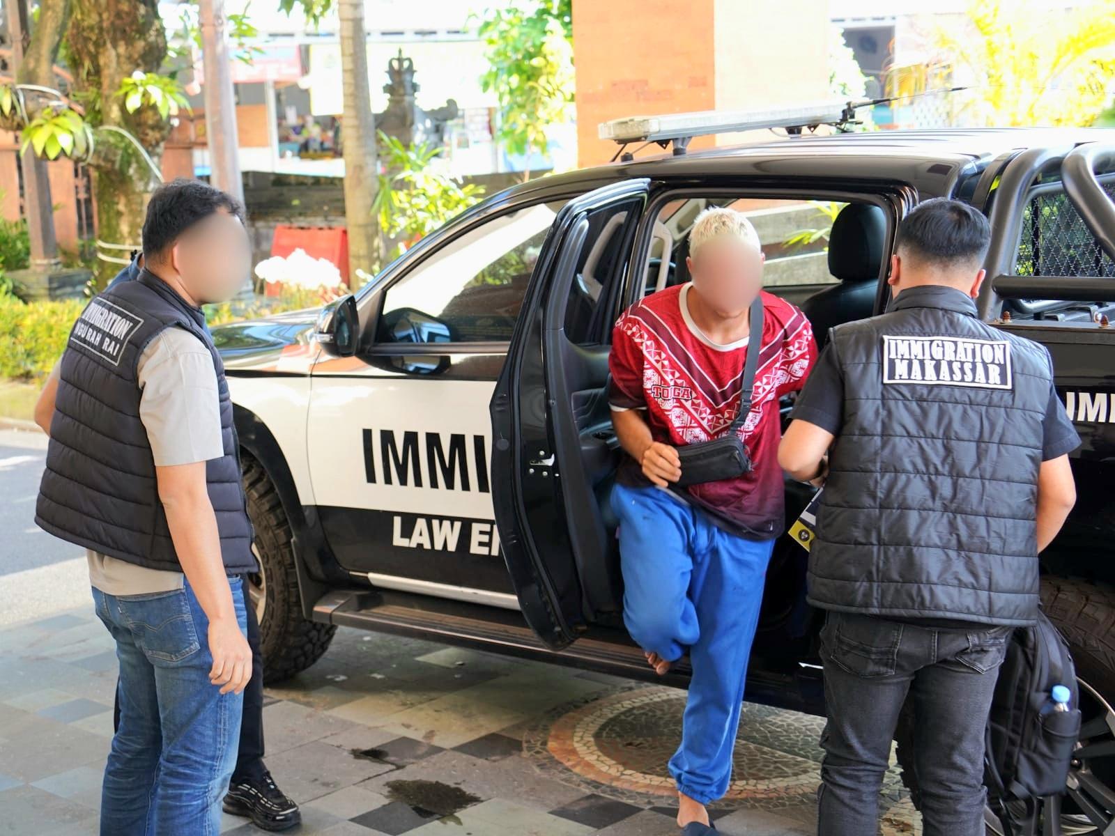 Petugas Imigrasi Ngurah Rai mengawal warga negara asing (WNA) asal Belgia berinisial SD (tengah, berbaju merah) saat proses pendeportasian menuju negara asalnya, Kamis (2/4/2026). (Balihotnews/Ist)