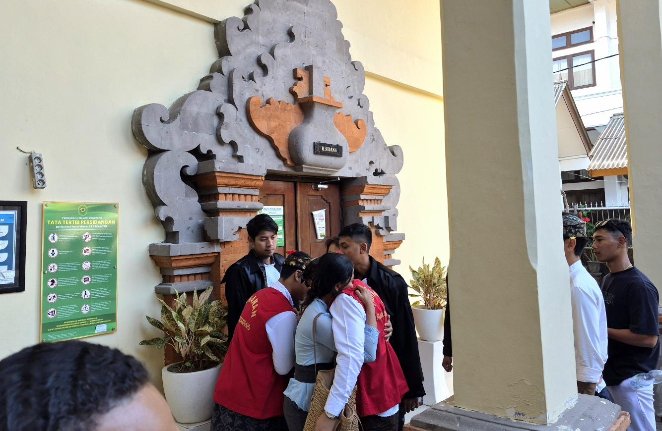 Momen kedua terdakwa kasus penganiayaan ibu tiri saat dijenguk keluarga usai sidang pembacaan pleidoi di Pengadilan Negeri (PN) Denpasar, Kamis (13/8/2026). (Foto: Balihotnews/dre)