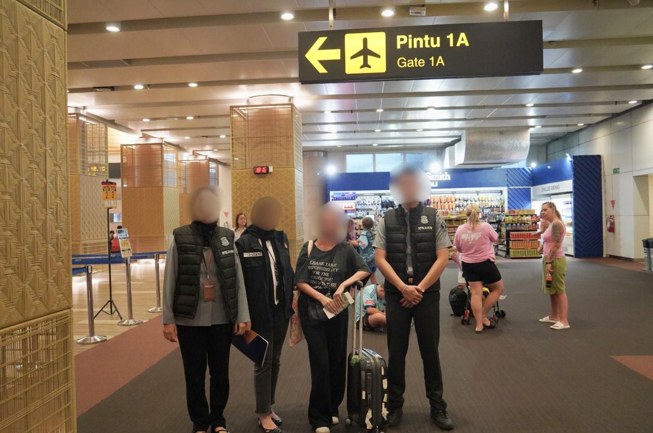 Seorang WNA Prancis berinisial KJB (tengah), dikawal petugas Imigrasi Ngurah Rai, sebelum dideportasi ke Paris, pada Senin, 3 November 2025. (Balihotnews/Ist).