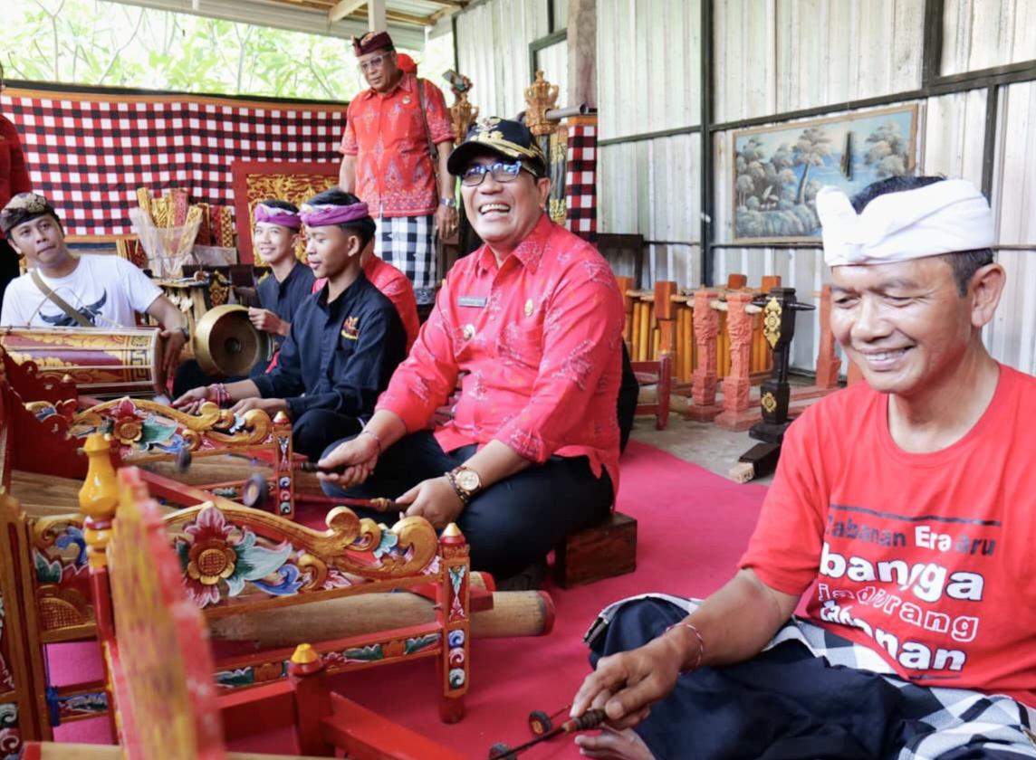 Bupati Tabanan I Komang Gede Sanjaya mencoba gamelan rindik saat hadir dalam program Bupati Ngantor di Desa (Bungan Desa) di Desa Antap, Kecamatan Selemadeg, Selasa (25/11/2024). (Balihotnews/red)