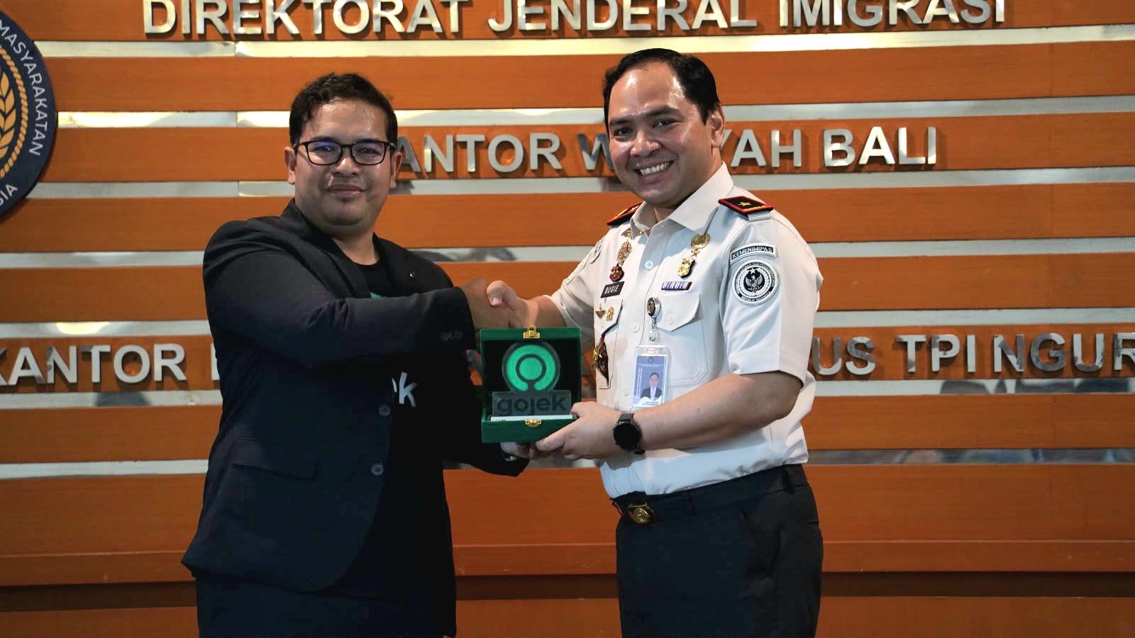 Kepala Kantor Imigrasi Ngurah Rai Bugie Kurniawan (kanan) bersama perwakilan Gojek usai peresmian inovasi pengantaran dokumen paspor melalui fitur GoSend. (Balihotnews/Ist)