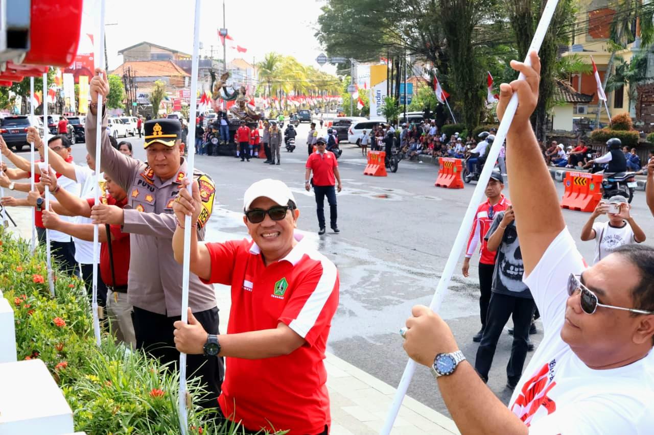 Bupati Tabanan I Komang Gede Sanjaya menancapkan bendera Merah Putih untuk mengawali parade bentangan bendera 100 meter di Taman Perjuangan Singasana, Tabanan, Selasa (4/8/2026). (Balihotnews/red)