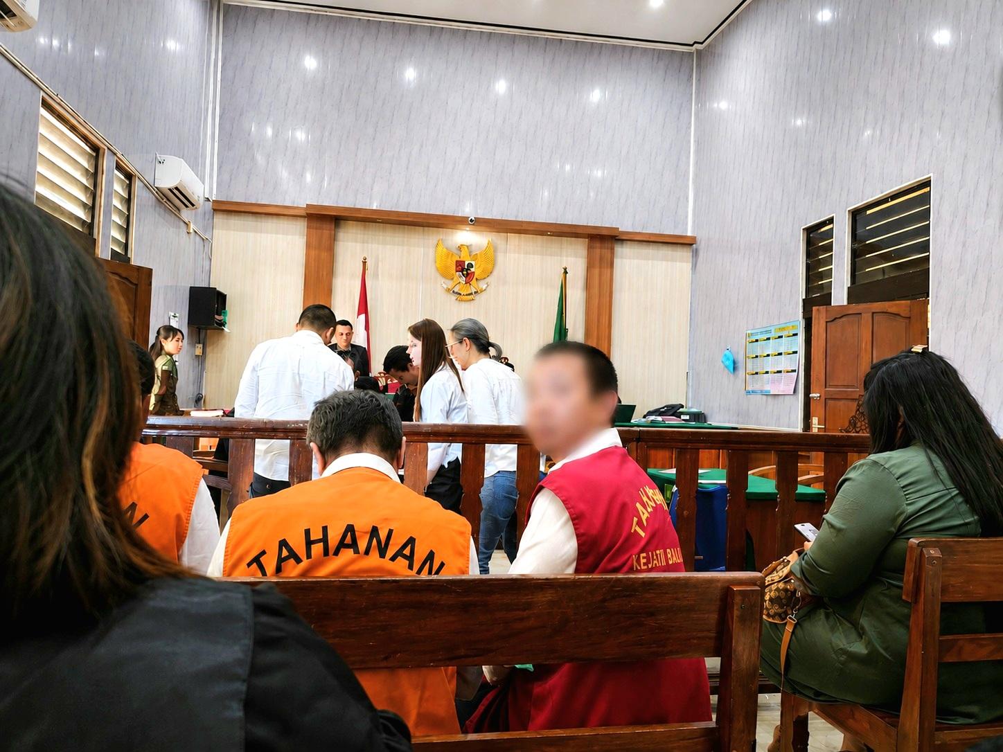 WNA asal Tiongkok berinisial C.H. (rompi merah) saat menjalani persidangan di PN Denpasar, Selasa (1/9/2026). Ia diadili usai tertangkap menggunakan paspor Malaysia palsu di Bandara Ngurah Rai. (Balihotnews/red)